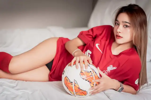 美女穿红色球衣抱足球侧卧床上人物电脑壁纸