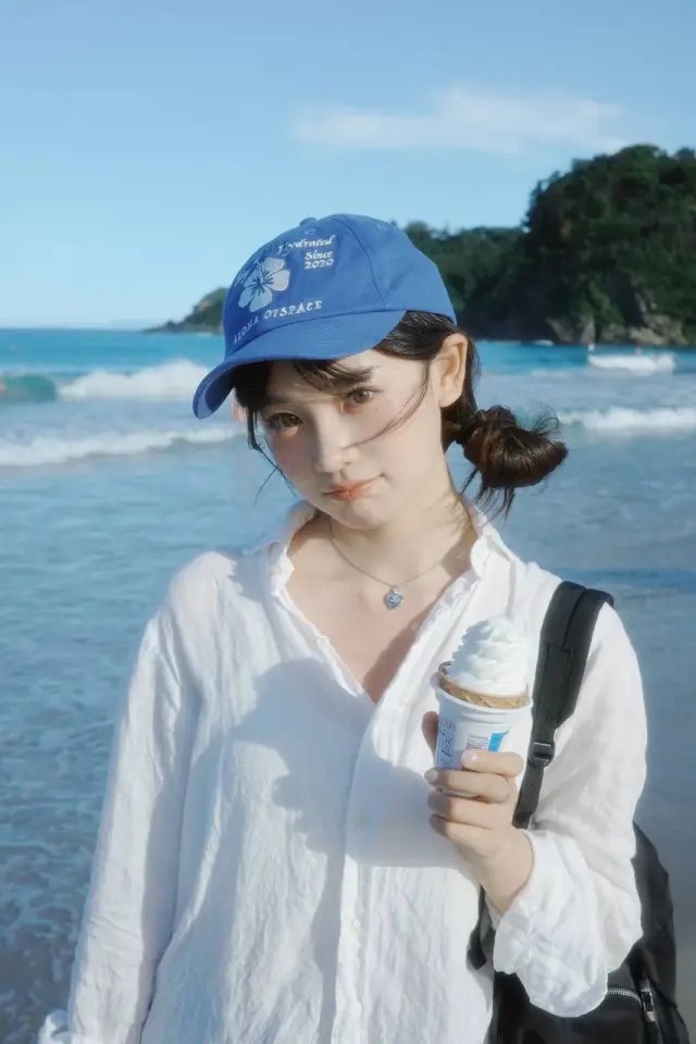 蓝帽白衫女生海边持冰淇淋人物手机壁纸