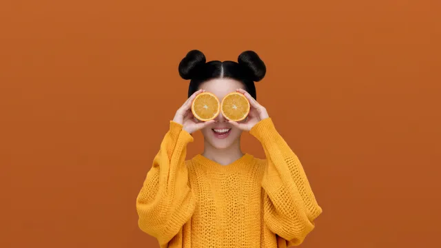 橙色毛衣女孩双手持橙子遮眼俏皮可爱电脑壁纸