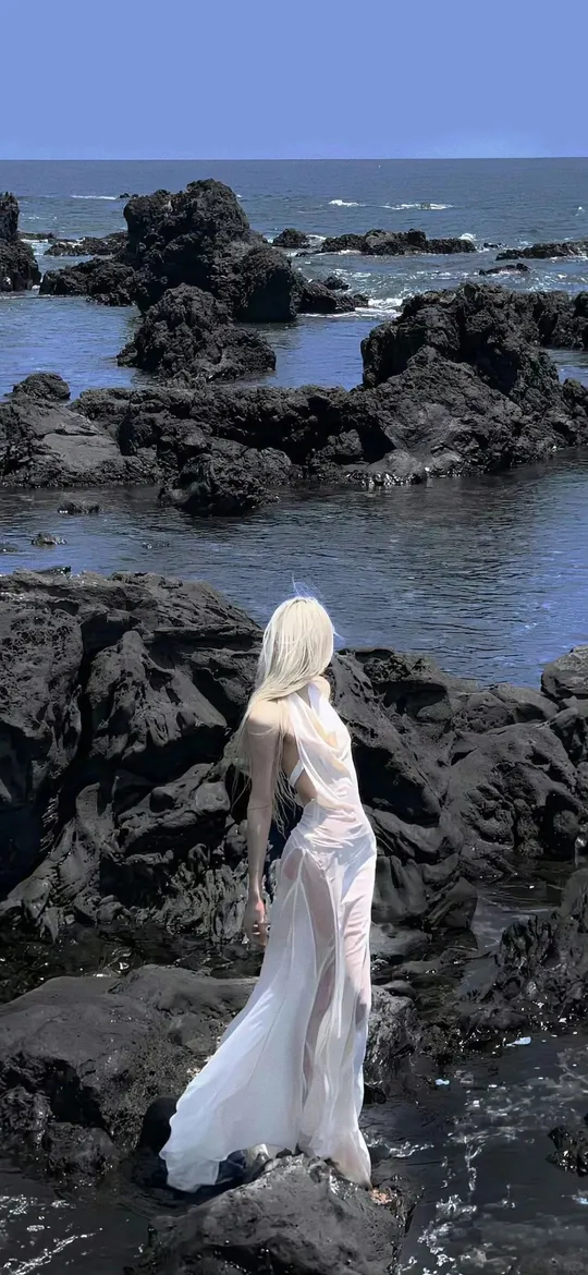 黑发女子海边岩石凝望海景手机壁纸