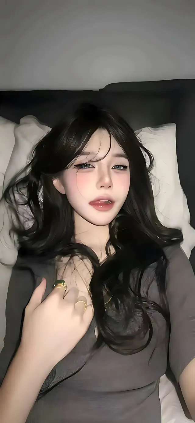 黑发蓝眼少女躺卧床头轻抚胸前手机壁纸