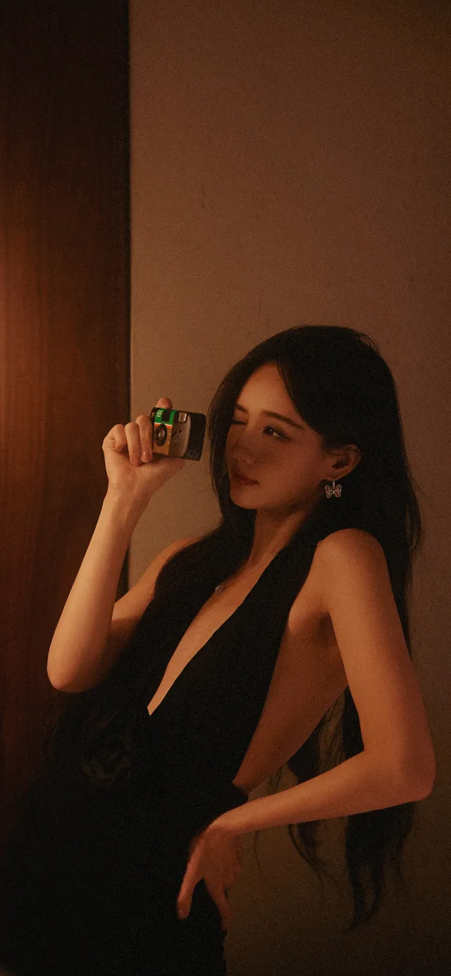 黑裙美女持相机侧身回眸室内写真美女手机壁纸